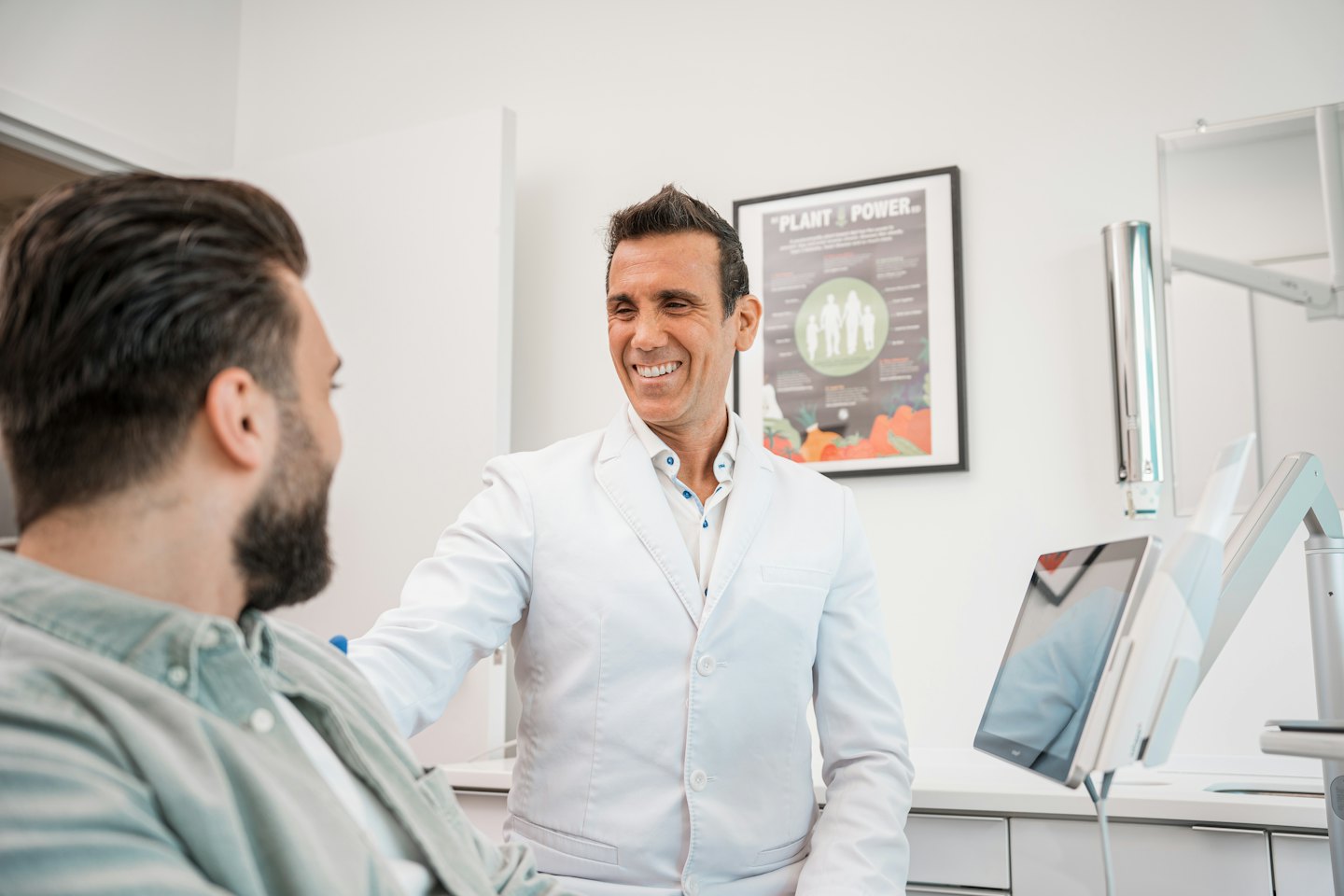 Medico sorride parlando con un paziente in una clinica moderna.
