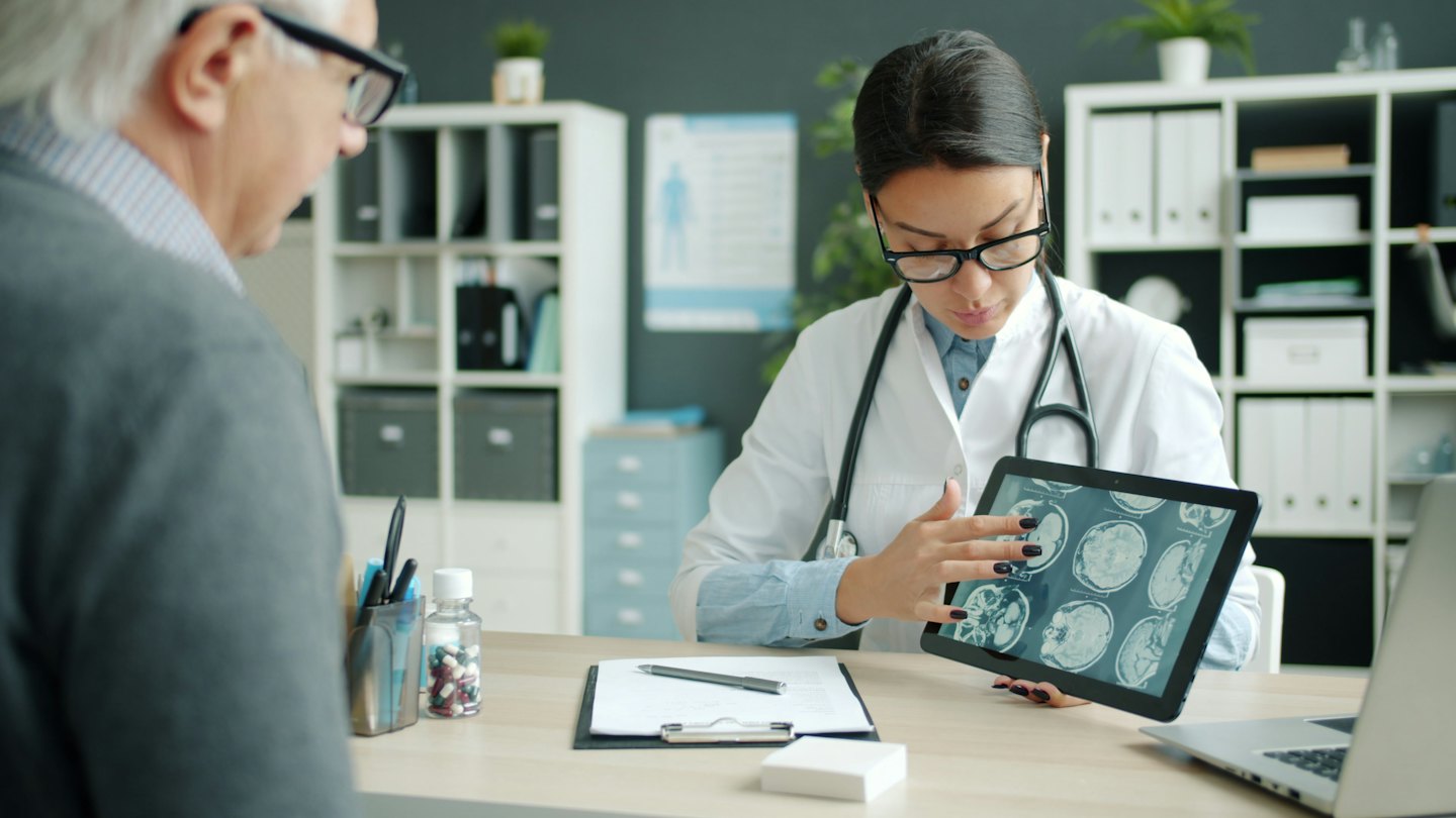 Medico che spiega delle scansioni mediche su un tablet a un paziente.